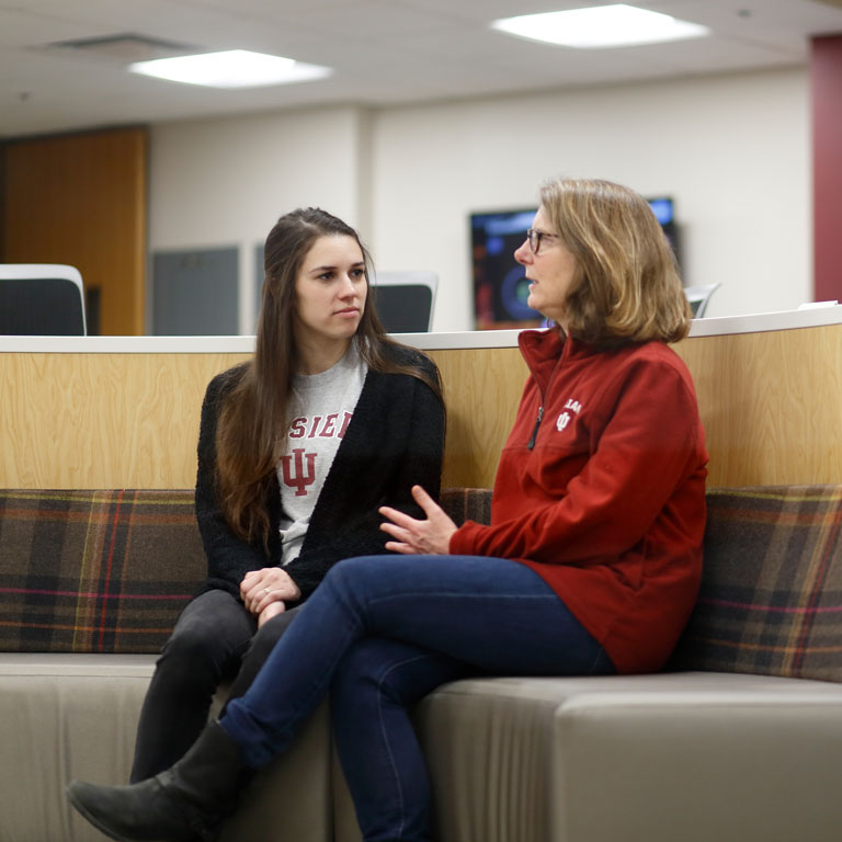 Female mentee listening to female mentor, sitting on a couch.